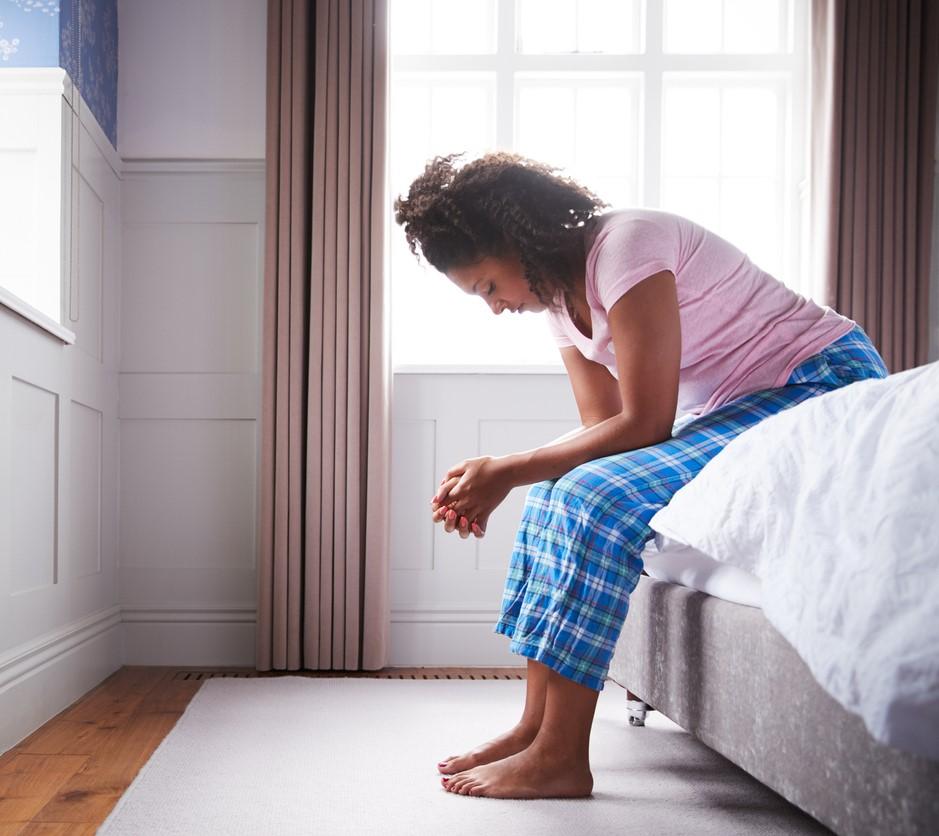 Exhausted woman sitting on edge of bed
