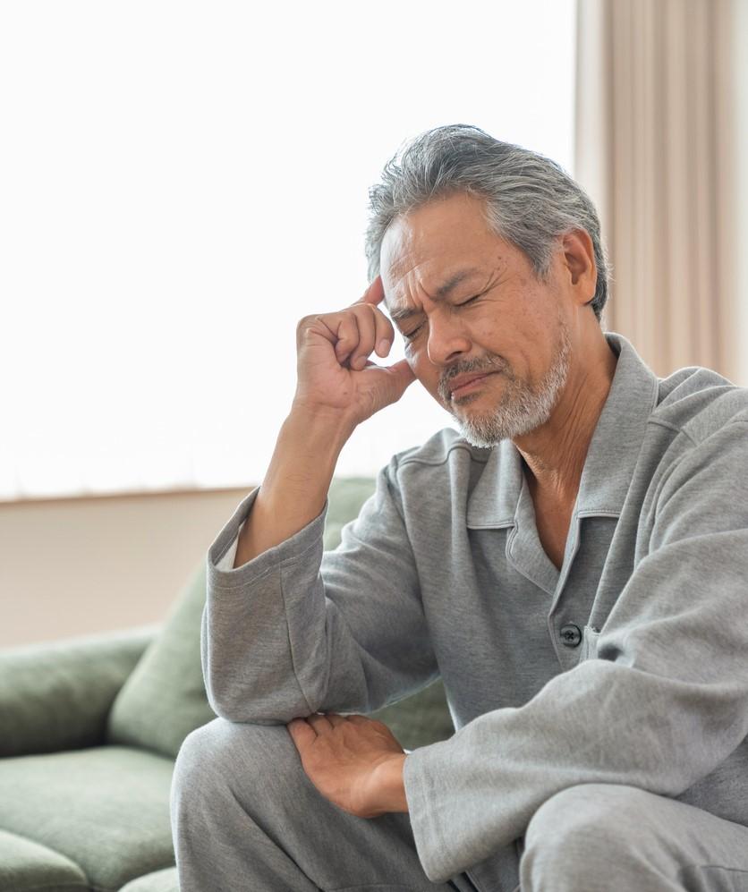 Fatigued older man sitting on couch