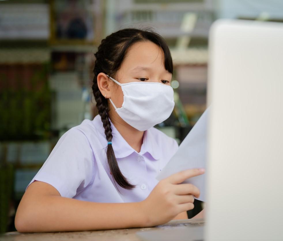 Girl wearing mask doing homework