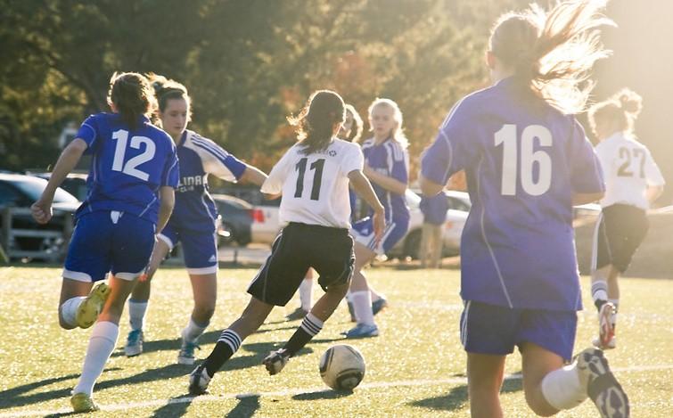 Girls playing soccer on sunny field