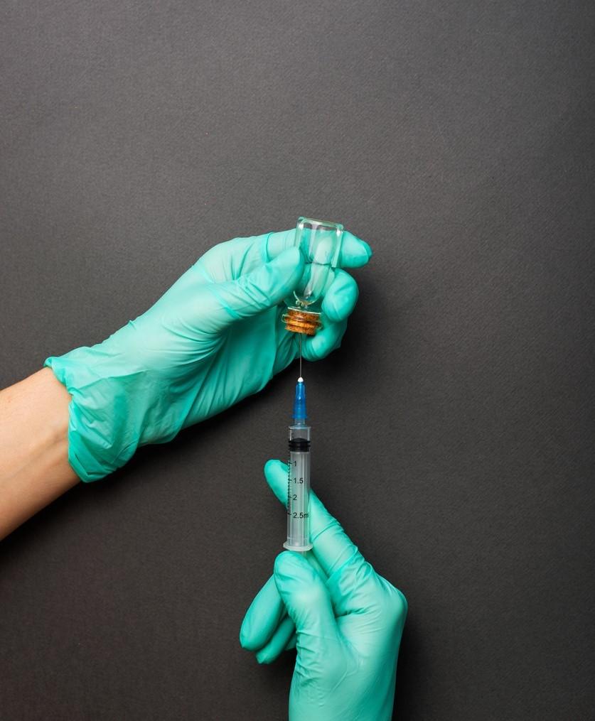Gloved hands preparing vaccine in syringe