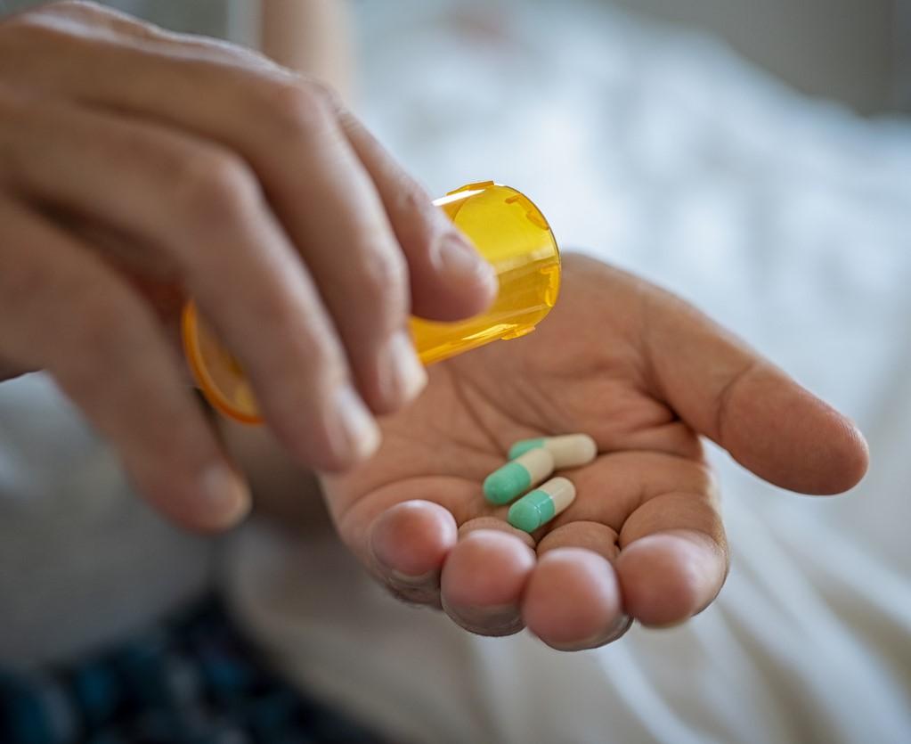 Green and white capsules in person's hand
