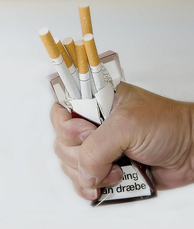 Hand crushing a pack of cigarettes