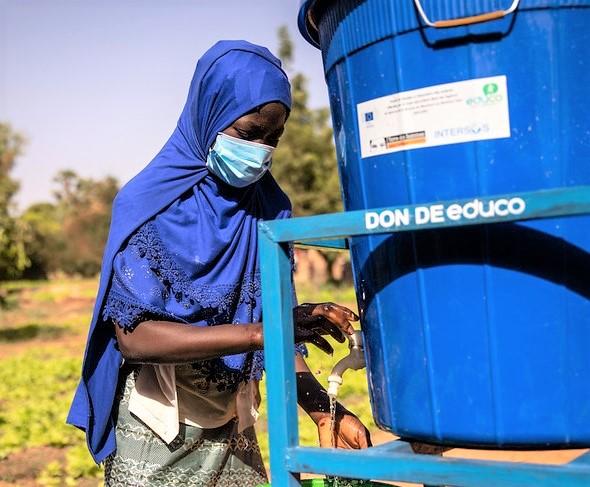 Girl wearing mask in Africa washing hands