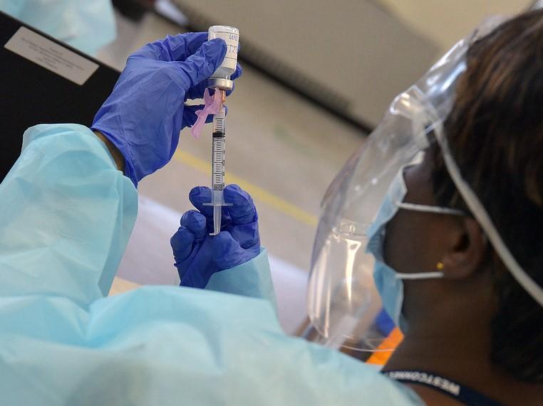 Healthcare worker drawing COVID vaccine into syringe