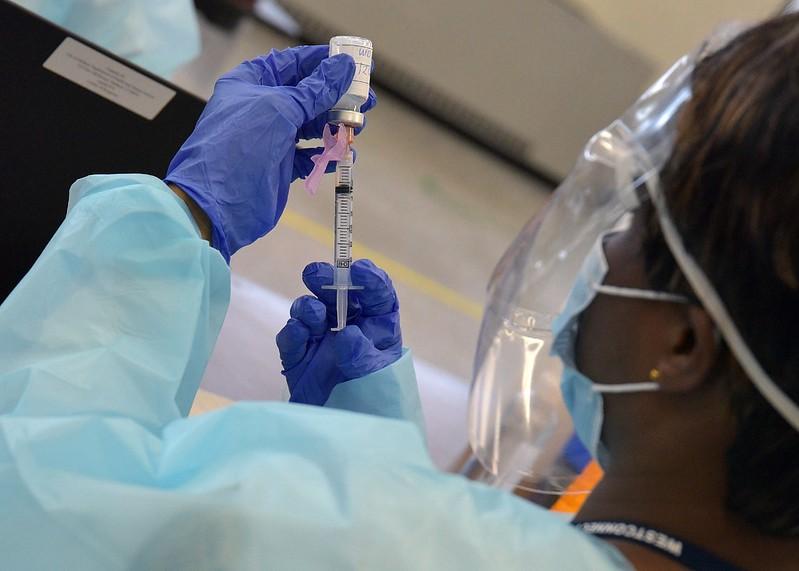 Healthcare worker filling COVID vaccine syringe