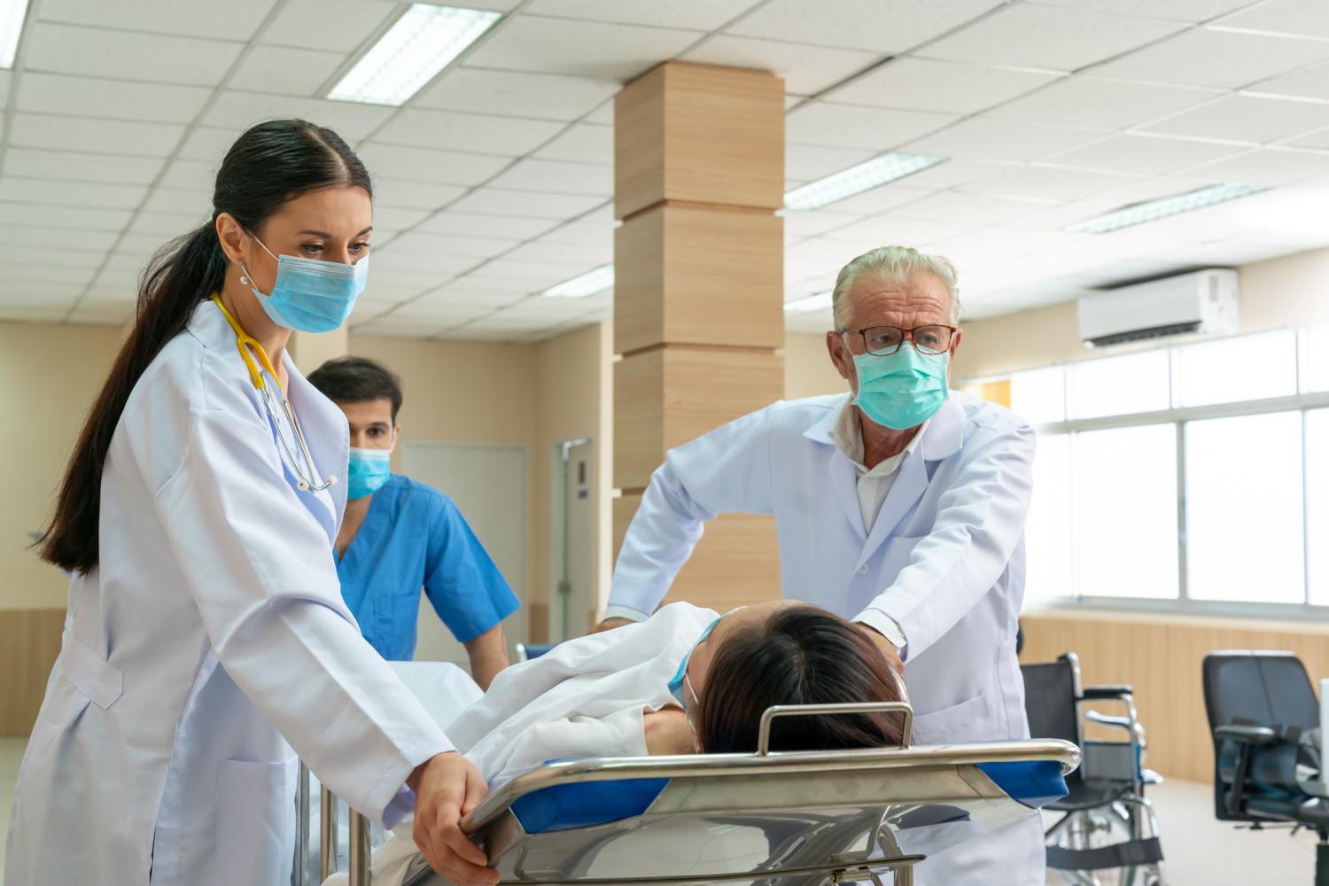 Healthcare workers rush in a patient on a hospital bed.