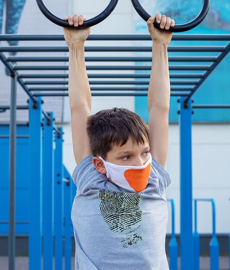 Boy wearing mask and hanging on rings