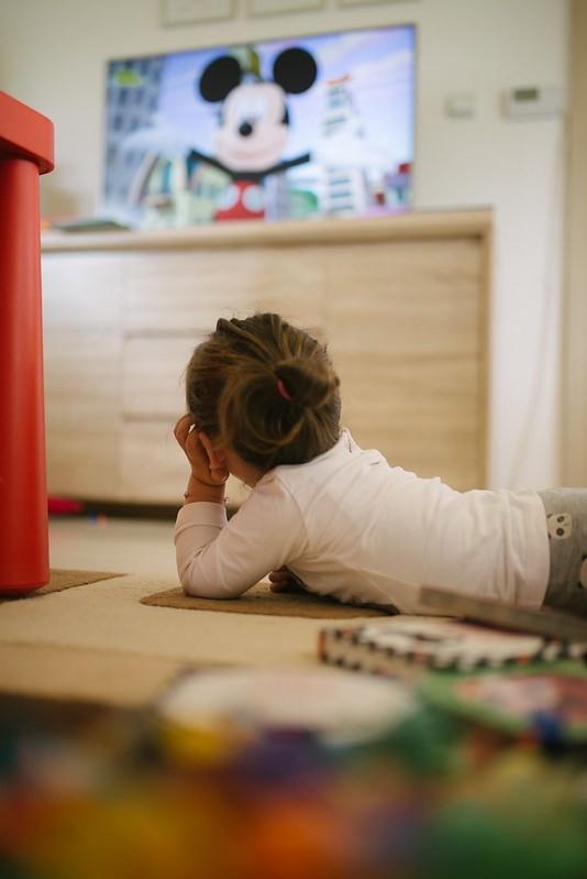 Little girl watching Mickey Mouse on TV