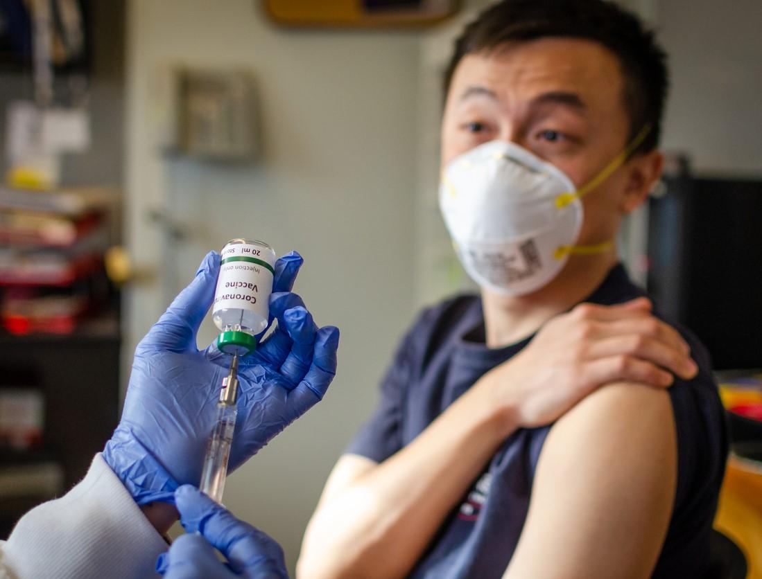 Man rolling up sleeve for COVID shot