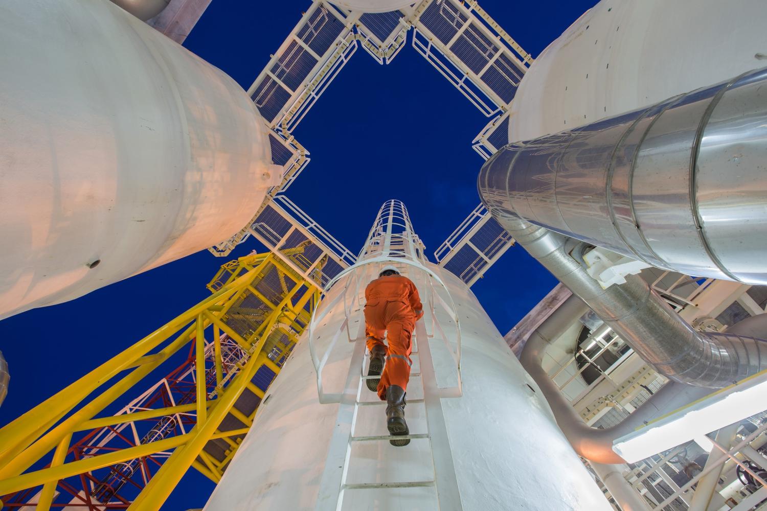 Man climbing tower at gas oil plant