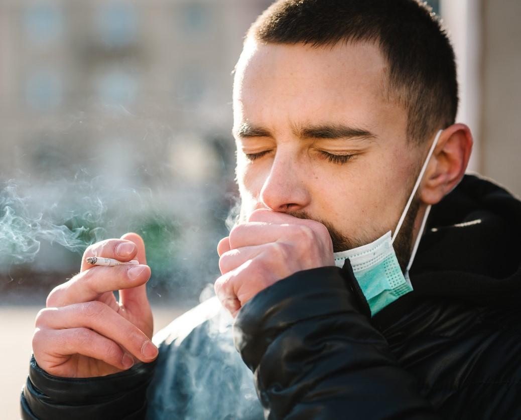 Man with surgical mask smoking outside