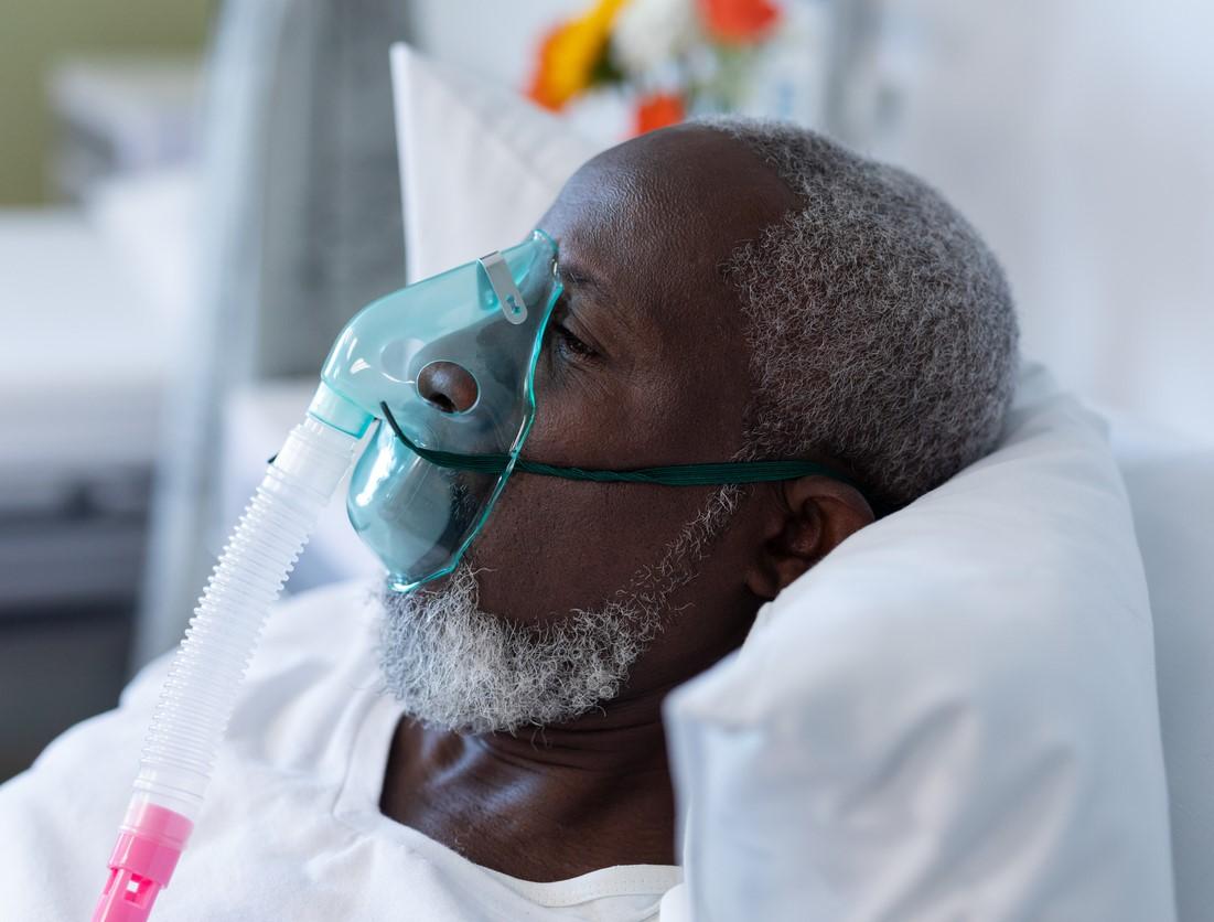 Man wearing oxygen mask in hospital bed