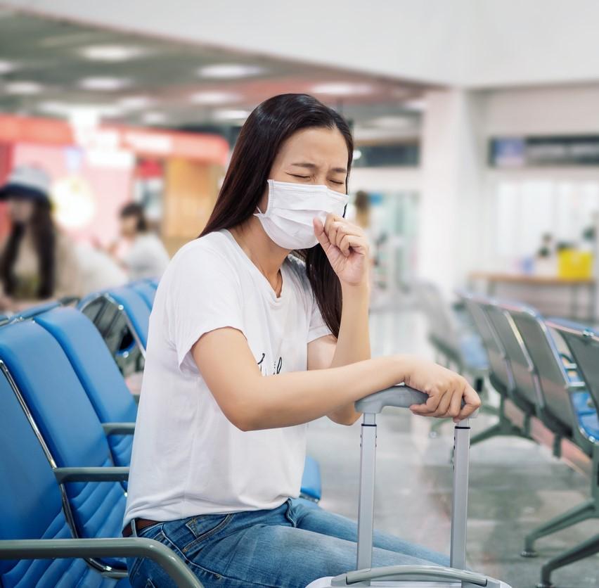 Mask-wearing tourish coughing in airport