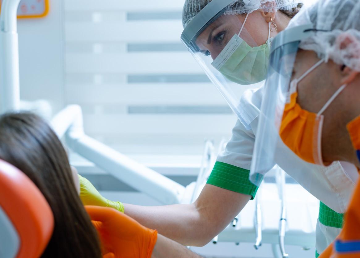 Masked dental workers with patient