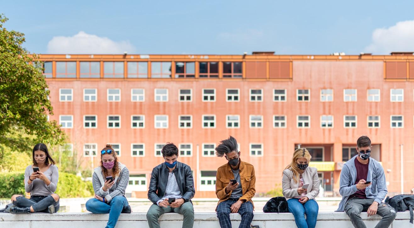 Masked students lined up on wall outside school