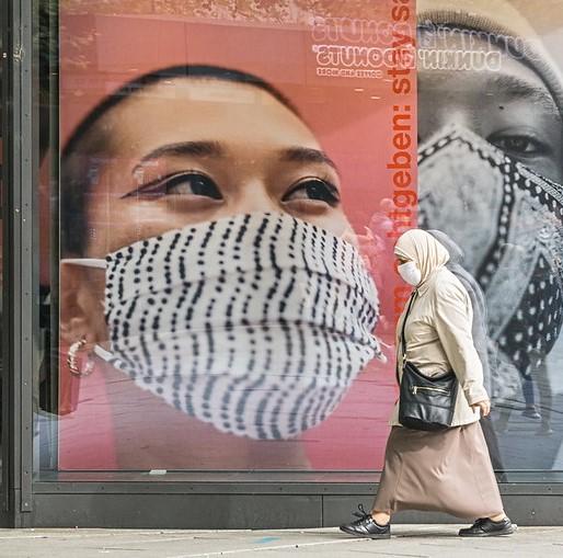 Masked woman walking in front of masking signs