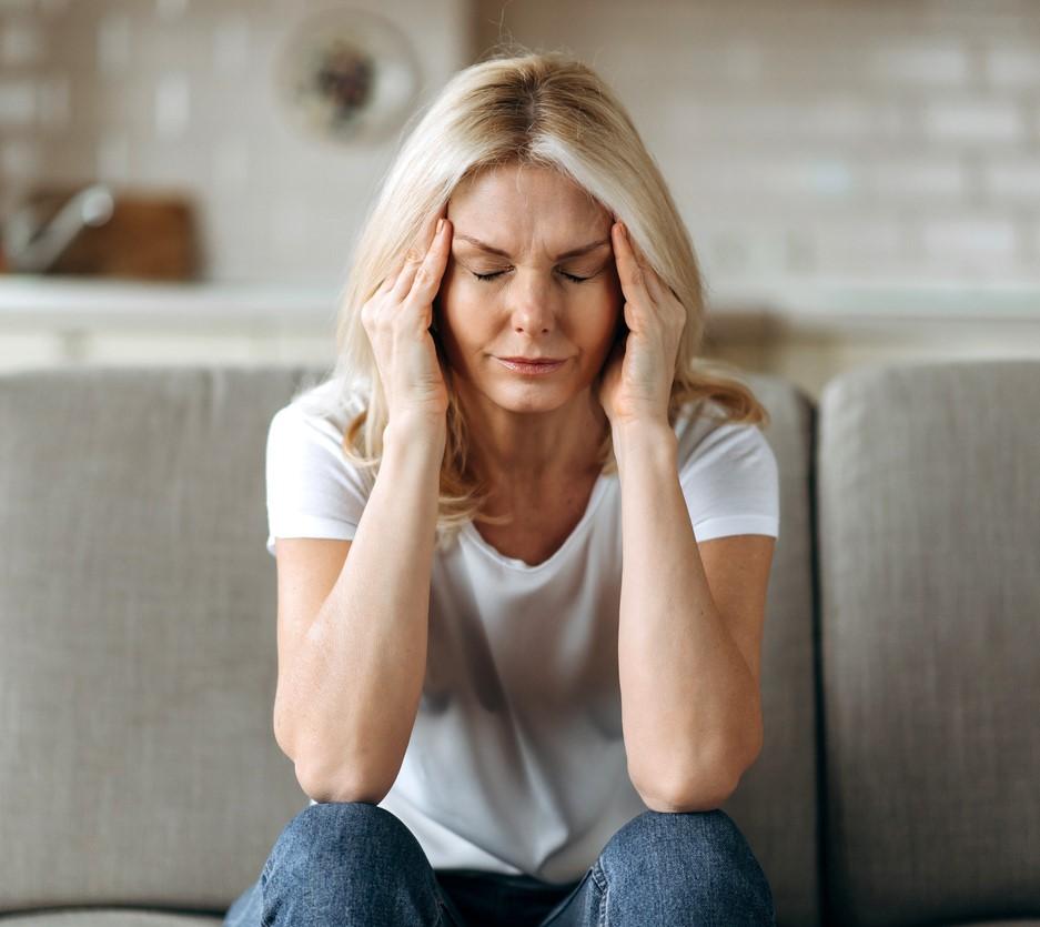 Middle-aged woman with headache sitting on couch