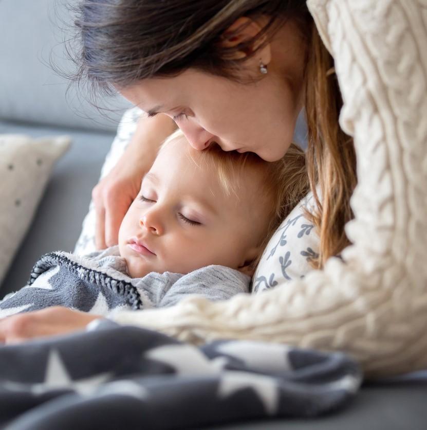 Mom kissing sick boy on forehead