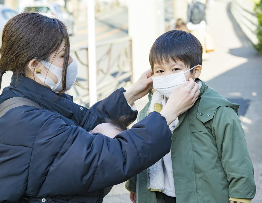 Mom putting mask on young son