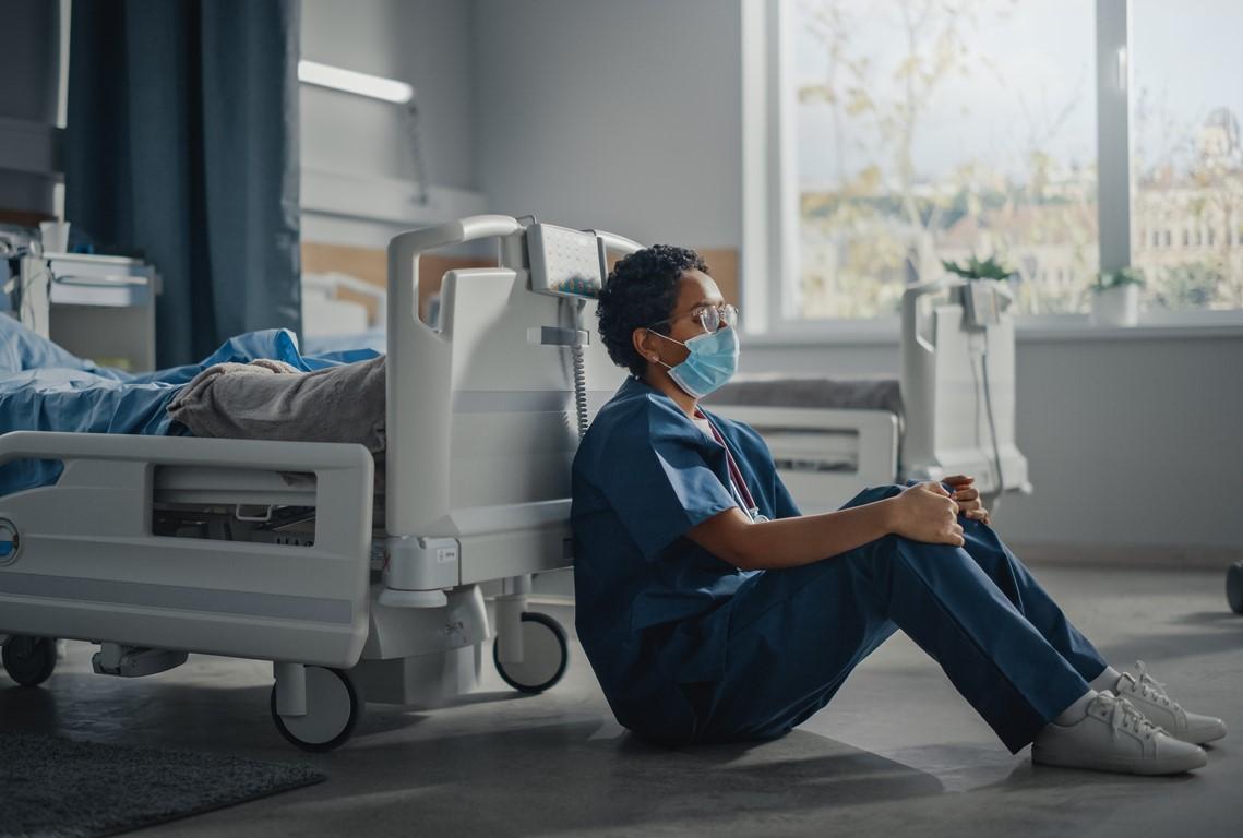 Sad nurse next to empty hospital bed