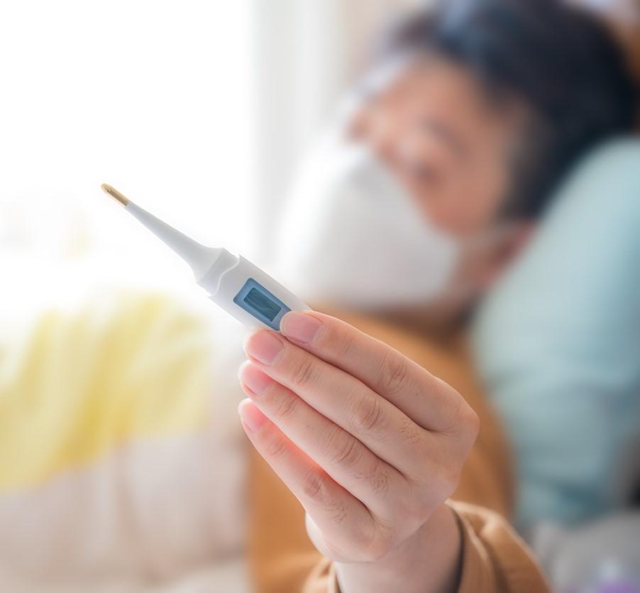 Sick man in bed reading thermometer