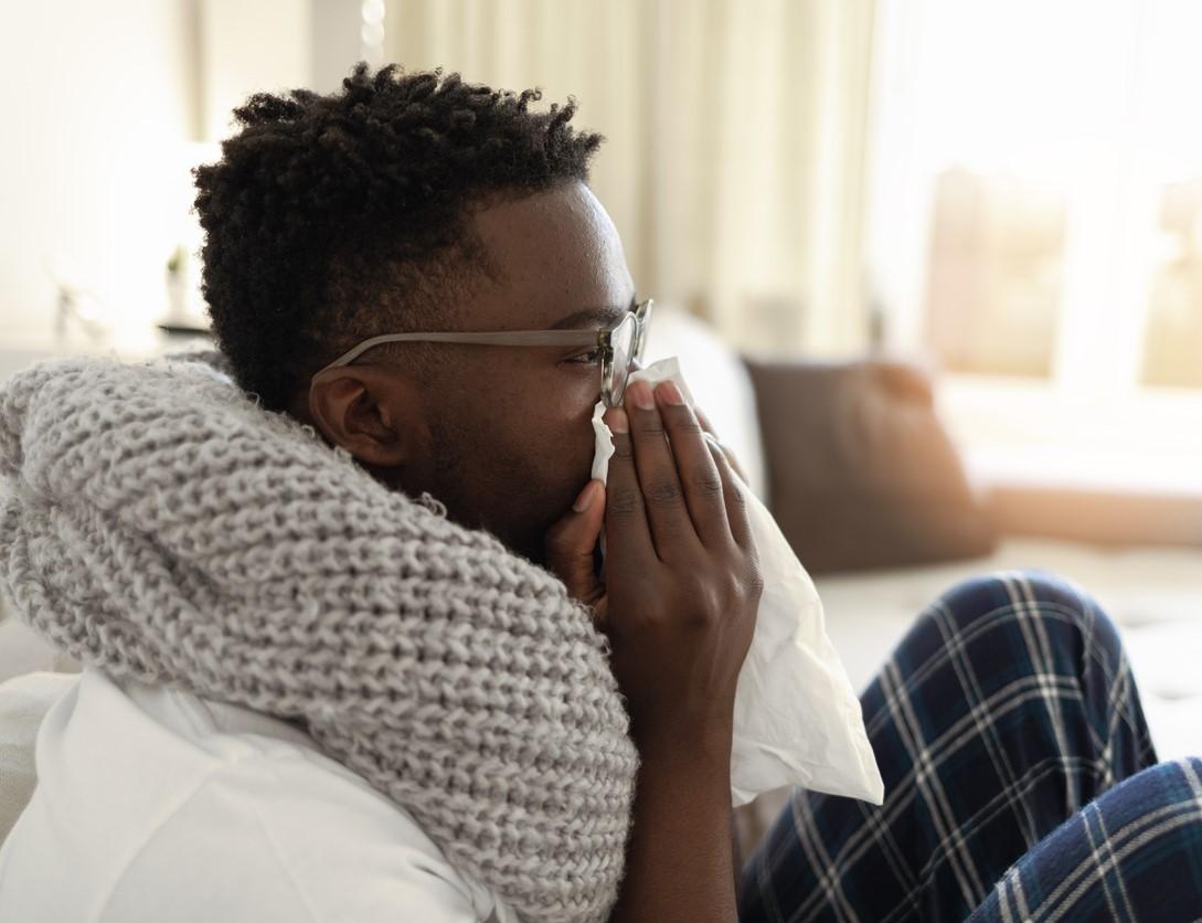 Sick man on couch blowing nose