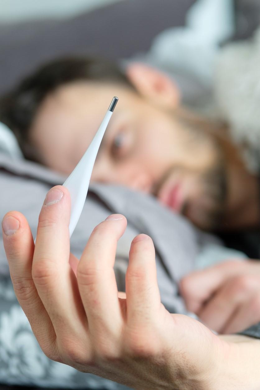 Sick man with thermometer