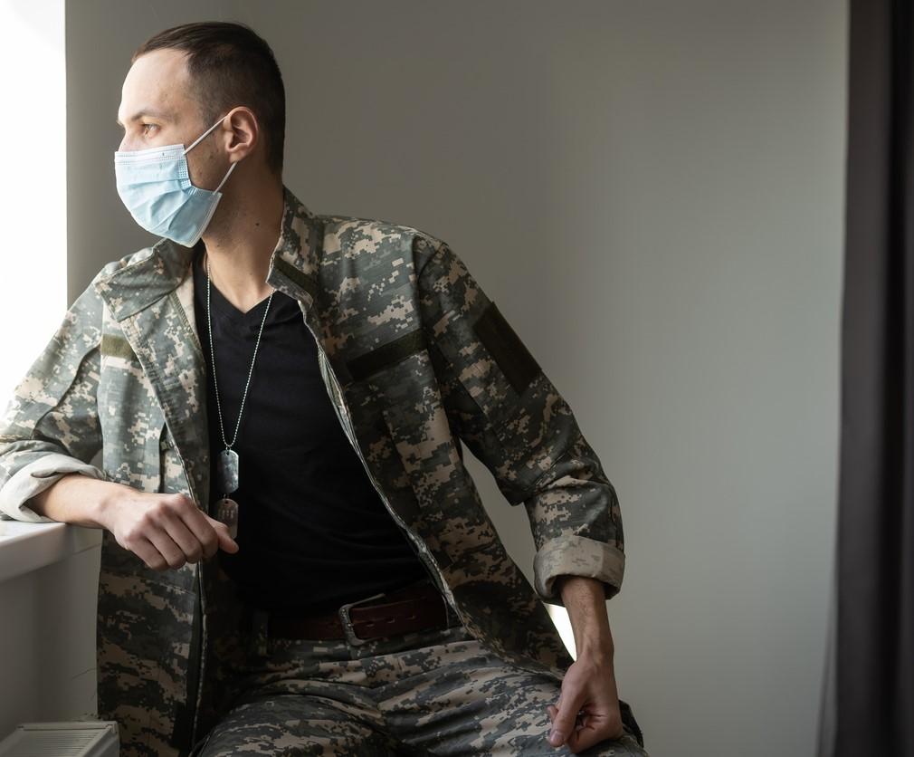 Soldier wearing mask and looking out window