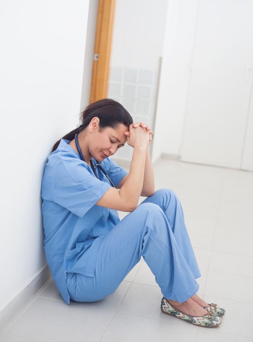 Stressed-out nurse sitting on floor