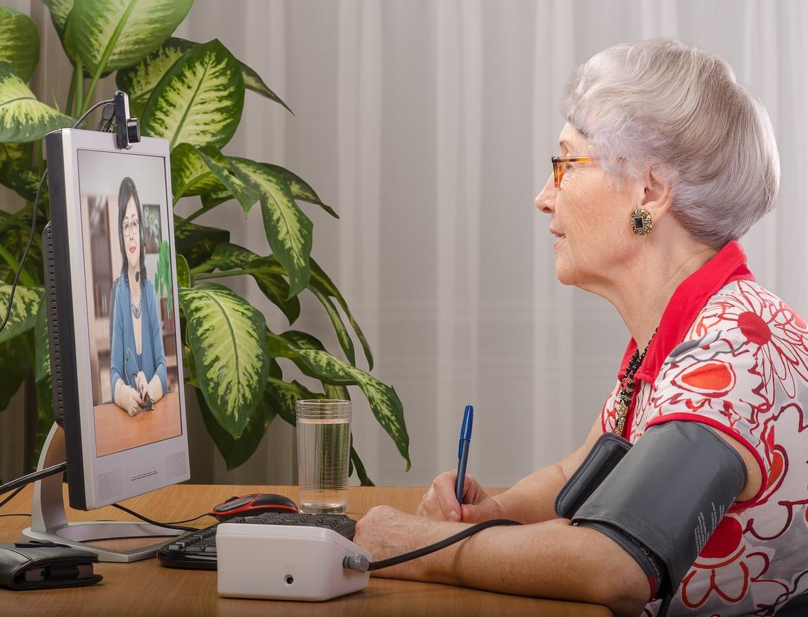 Older woman telemedicine wearing blood pressure cuff