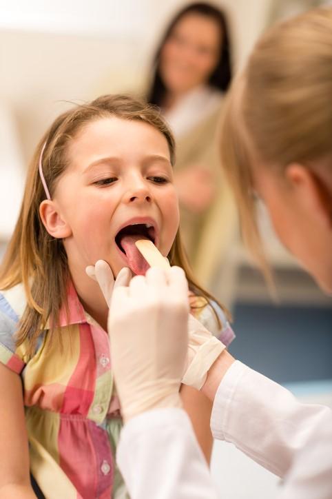 Doctor examining girl's throat