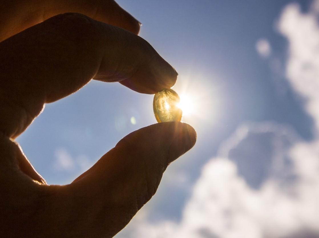 Vitamin D capsule held in front of sun