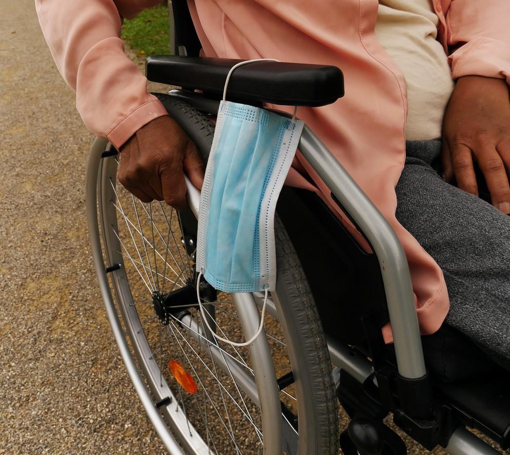 Medical mask hanging on woman's wheelcair
