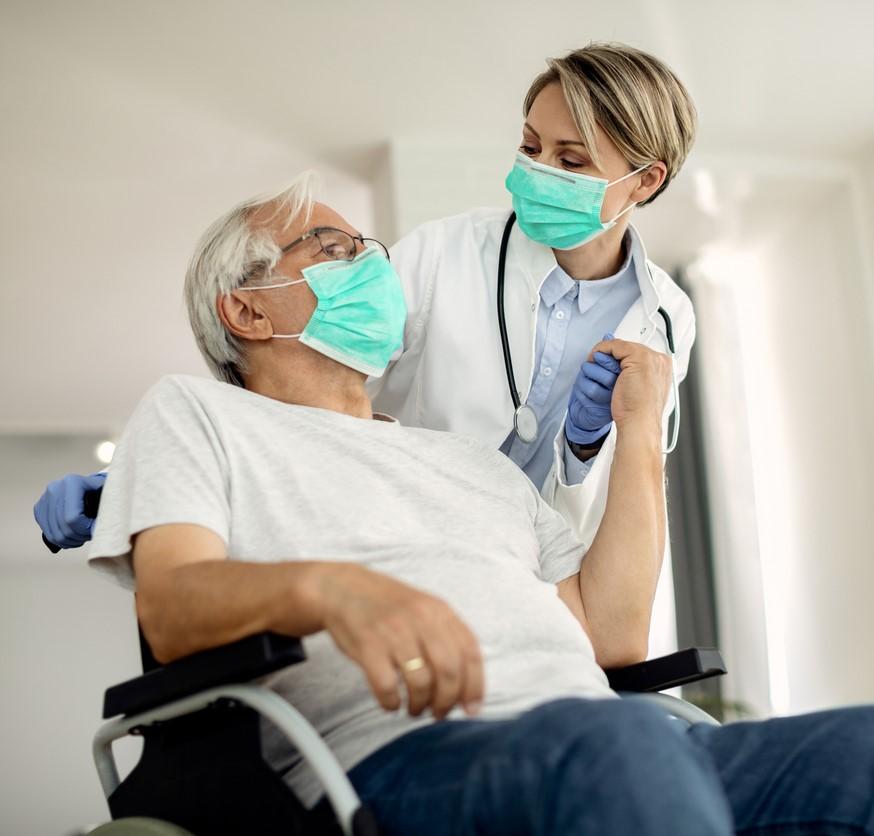 Wheelchair patient with doctor, both wearing masks