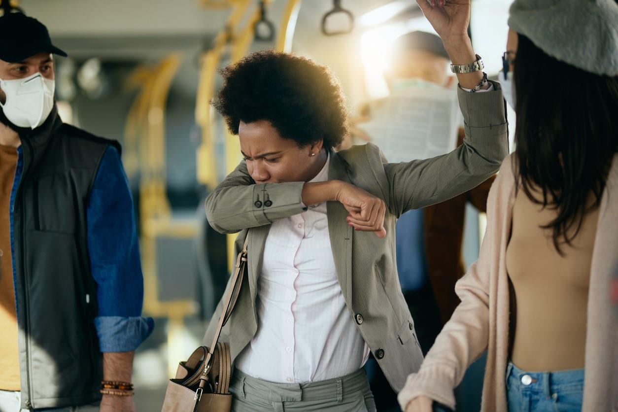 Woman coughing into sleeve on train