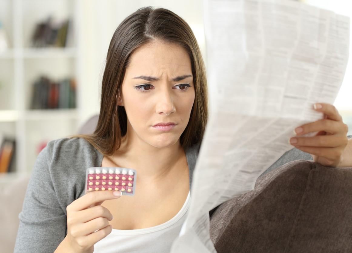 Woman with pill packet and long instruction sheet