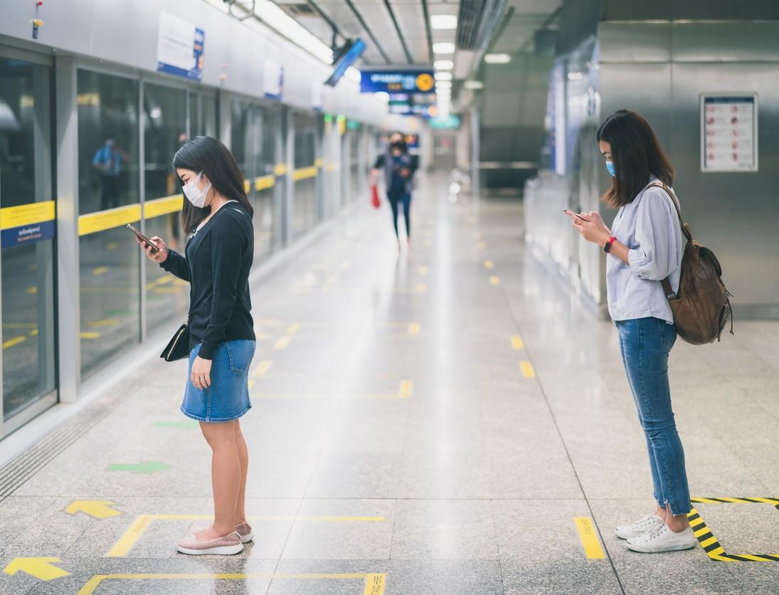 Women physically distancing at train station