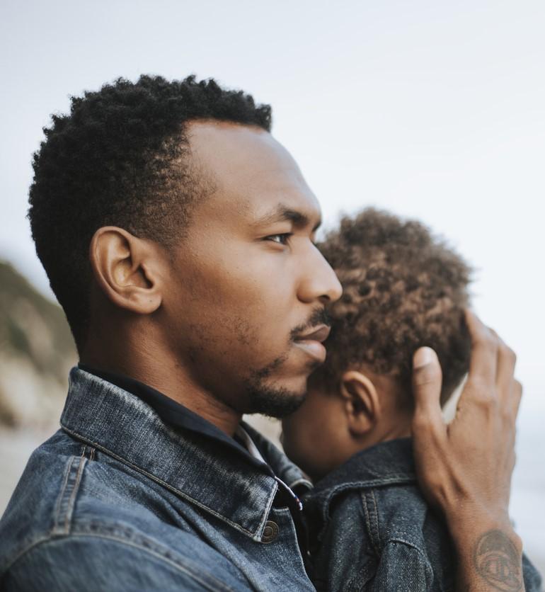 Young black dad holding son