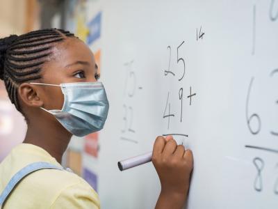 Schoolgirl wearing mask at whiteboard