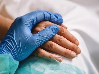 Gloved hand holding patient's hand