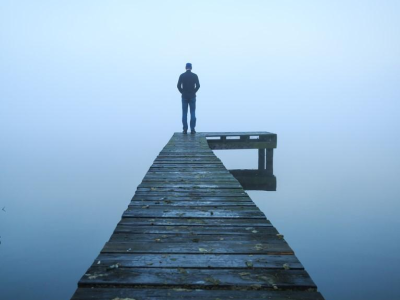 Person standing at end of dock in fog