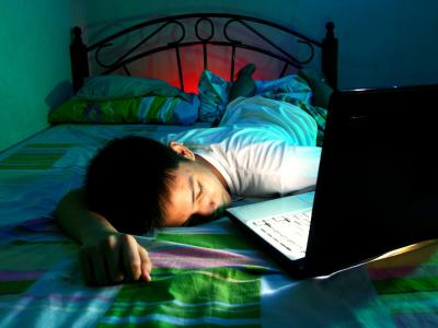 Teen boy asleep on bed with laptop