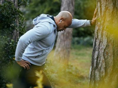 Tired man leaning on tree