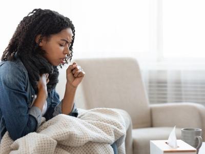 Young woman coughing on couch