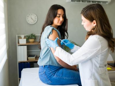 Young woman receiving a flu shot from female doctor