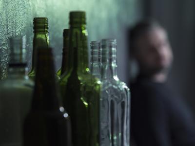 Alcoholic with empty bottle in foreground