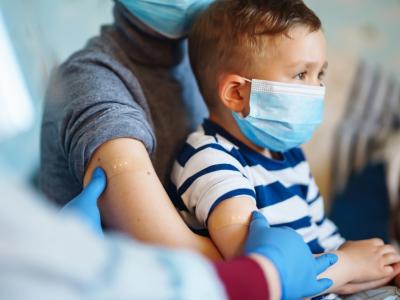 Boy on mom's lap with vaccine bandage on arm