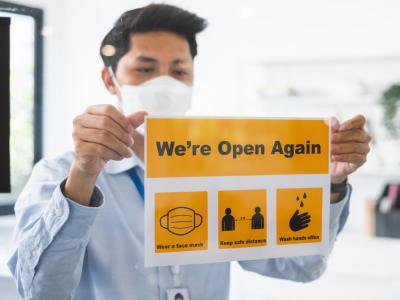 Businessman with "We're open again" sign