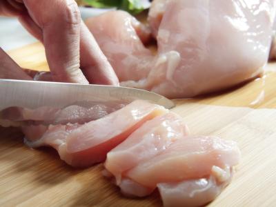 person cutting up raw chicken
